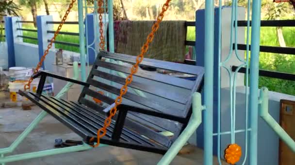 Balançoire vide dans l'aire de jeux pour enfants. Fer oscillant balançant vers l'avant et vers l'arrière de manière aléatoire. — Video