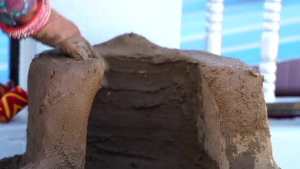 Mano femenina frotando arcilla y mortero de estiércol de vaca en la estufa de cerámica. Arte antiguo para formar estufa de arcilla. — Vídeos de Stock