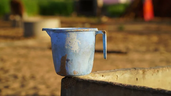 Gün ışığında kaba sütunlu kirli plastik bir kupa. Yıkanmak için eski, kirli bir kupa. Eski yeşil plastik bardak yakın plan..