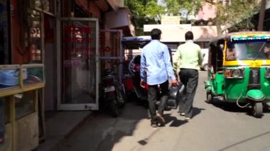 Yolda yürüyen Hintli erkeklerin arka planı. Yakıt deposunu elinde tutan bir adam. Yavaş çekim görüntüleri.