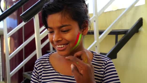 Pequena menina alegre coloração no rosto. Menina jogando cor e marcando Gulal ou Abhir na bochecha. Menina bonita com festival de cor bonita. — Vídeo de Stock