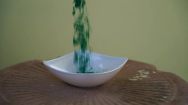Gökkuşağı bitkisel rengi havada uçuşuyor ve beyaz kasede sıçrıyor. Geleneksel organik renk festivali Holi.