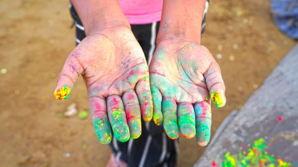 Human hand with Multi colors natural dyes. Flower rose color powder closeup on the human hand. Holi festival.