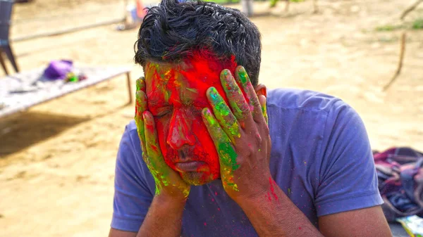 Stained color face of a Young adult man with Gulaal color. Festival color of Holi and man making joy and fun on color festival.