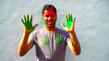Yeşil lekeli Holi oynayan mutlu görünümlü Hintli. Holi 'de renkli eli gösteren adam.