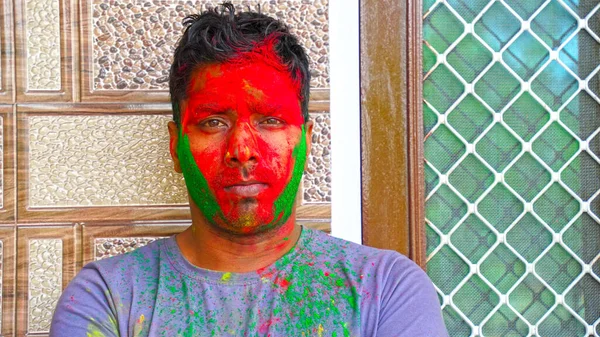 Indian culture Happy Guy making Holi festival with Gulaal or Abhir colors. Smeared face of colors.