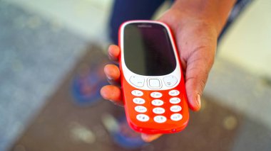 Selective focus on the keypad of a mobile. Beautiful red phone in Human hand. Keypad phone concept.