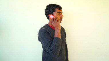Indian man holding a mobile phone and busy to talking someone. Adult man shot during make a call.