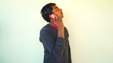 A man inspecting roof interior while make a call. Closeup shot of Young guy communicating someone with a red color cellphone.