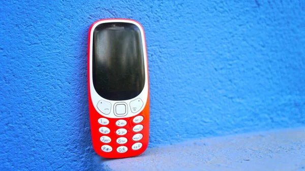 Close up of old 2G technology cellphone, with blue wall background. Old communication series of Mobile phone.