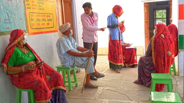 08 Nisan 2021 - Akhepura, Sikar, Hindistan. Bir grup kadın ve erkek Covid aşısı için hastanede oturuyorlar. Covid salgını 2019 Hindistan 'da ikinci dalga etkisi.