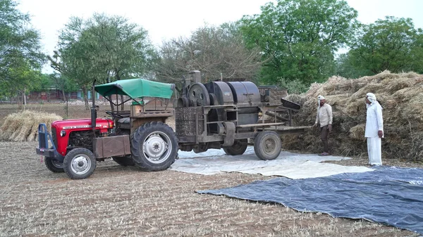 畑で小麦やライ麦を収穫するために脱穀機を使用する農家。2021年4月8日インド、シカル州アクヒブラー付近の写真. — ストック写真