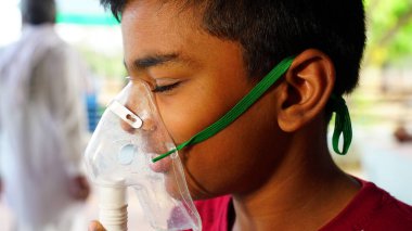 Ağır grip ve öksürük geçiren Asyalı çocuk. Öksürük humması için maske takan küçük bir çocuk.. 