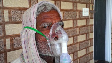 30 Nisan 2021, Jaipur, Rajasthan, Hindistan. Corona salgını ve Hindistan 'da ters etki. Akciğer enfeksiyonu ve Covid virüsü olan yaşlı bir adam. Yüzünde acil durum oksijen maskesi.