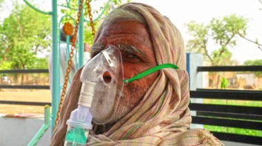 30 Nisan 2021, Jaipur, Rajasthan, Hindistan. Corona salgını ve Hindistan 'da ters etki. Akciğer enfeksiyonu ve Covid virüsü olan yaşlı bir adam. Yüzünde acil durum oksijen maskesi.
