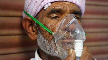03 Mayıs 2021 - Reengus, Sikar, Hindistan. Yaşlı Hintli çiftçi hastanenin dışında Cannula ile acil durum oksijeni alıyor. Hindistan 'daki Covid kavramına bağlı ciddi nedenler.