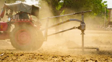 07 Mayıs 2021 - Reengus, Sikar, Hindistan. Toz uçuşu ve traktörle çalışan çiftçi. Yeni yeniliklerle tarım kavramı.