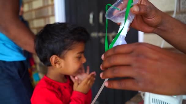 Un membre de la famille retire le masque du visage des enfants. Indien petit garçon se sentir bien après inhalation. — Video