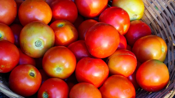 Close up fresh red tomatoes in market in Jaipur, India. Tomatoes with bowl on a blurred background close up