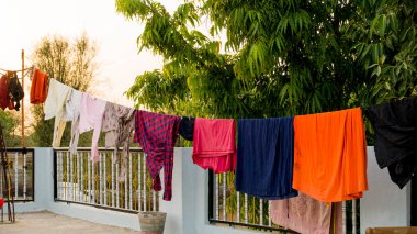 On roof, Rope with clean clothes outdoors on laundry day. Colorful clothes hanging in clothesline.
