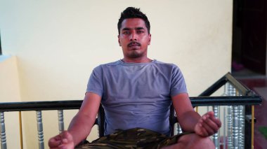 Sağlıklı bir adam evdeki paspasın üzerinde otururken bacak esneme egzersizi yapar. Sağlıklı yaşam tarzı, kapalı alanda egzersiz.