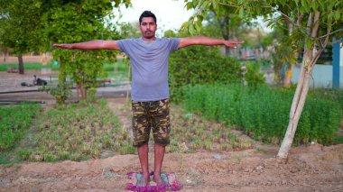 Genç Hintli adam Yoga pozisyonunda duruyor ve evde meditasyon yapıyor. Dünya çapında yoga günü konsepti.