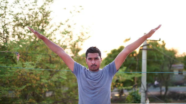 Sağlıklı genç adam parkta yeşil çimenler üzerinde esneme egzersizi yapıyor. Yoga günü konsepti