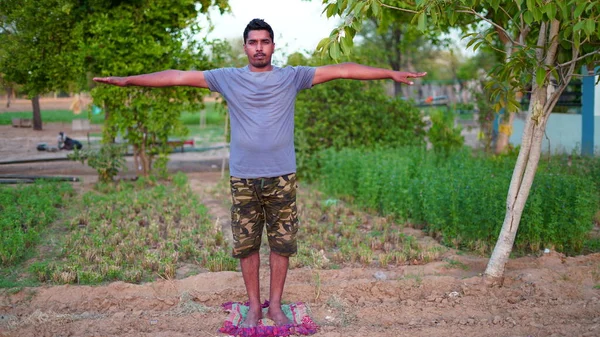 Genç Hintli adam Yoga pozisyonunda duruyor ve evde meditasyon yapıyor. Dünya çapında yoga günü konsepti.