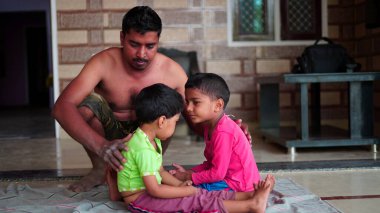 Portrait of trainer helping while kids are practising yoga by bending backwards on mats at home.