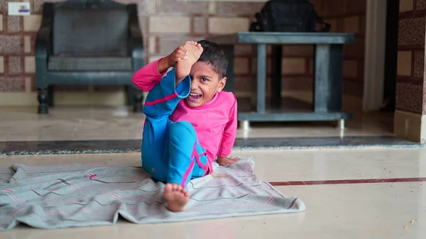 Indian little boy is smiling while doing yoga in hall at home. Worldwide yoga day concept.