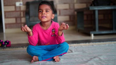 Indian little boy having fun in living room. Healthy lifestyle and Worldwide yoga day concept.