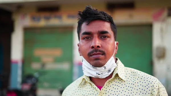 マスクとシャツを身に着けているインド人男性のフロントショット上のぼやけた市場の背景に深刻な顔 — ストック写真