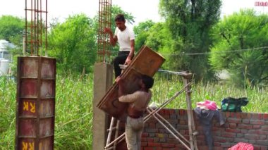 Sivil üniformalı inşaat işçisi inşaat demirlerini büküyor. Endüstriyel tırmanışçılar uzun vadede çalışırlar.
