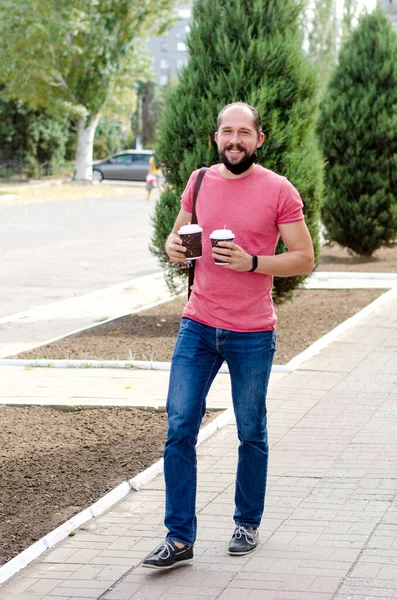 Sakallı genç adam elinde iki bardak kahve taşıyor. 