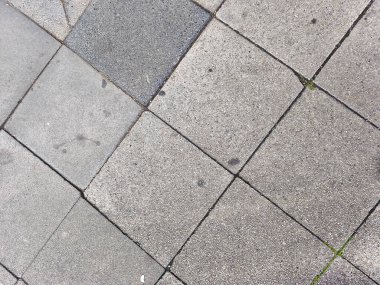 Diagonal pattern of rough gray paving stones creating abstract outdoor textured surface background