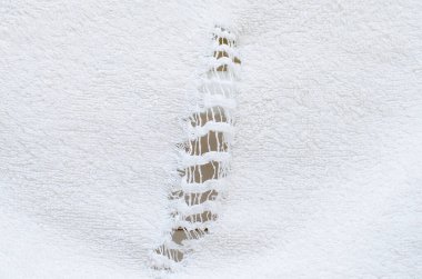 Yıpranmış beyaz havlu üzerinde dikey yırtık ve delik.