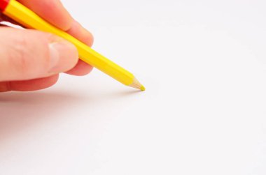 Bu resim, boş bir kağıt parçasının üzerinde duran, yaratıcılığı, ilhamı ve sanatsal ifadenin başlangıcını sembolize eden parlak sarı bir kalemi tutan bir eli yakalar..