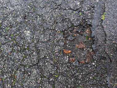 Hasarlı asfalt, çatlaklar ve küçük çukurlar, pürüzlü dokuyu ve yıpranmış yüzeyi gösteriyor. Kentsel bozulma, doku ve yol arka planı kavramları için mükemmel..