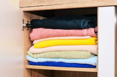 Banyo dolabında kullanıma hazır, çeşitli renklerde temiz ve katlanmış havlular var.