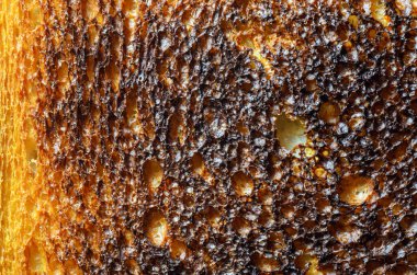 Bu makro çekim aşırı kızarmış ekmeğin karmaşık detaylarını gözler önüne seriyor, dokular ve renkler arasındaki zıtlığı vurguluyor