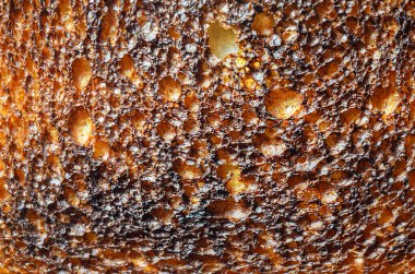 Bu makro çekim, bir tostun kabarık, kömürleşmiş dış yüzünü vurgulayan karmaşık detaylarını gözler önüne seriyor.