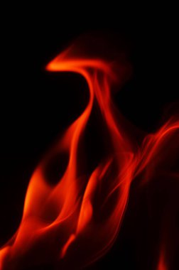 Kıpkırmızı alevler dans ediyor ve kıvrılıyor, karanlığa karşı büyüleyici bir görsel etki yaratıyor.