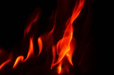 Alevlerin ateşli turuncu ve kırmızı renkleri koyu siyah arkaplanla çok güzel tezat oluşturuyor ve çarpıcı bir görüntü oluşturuyor.