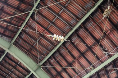 Perspektif, tavan yapısı ve elektriksel bileşenlerin benzersiz bir görüntüsünü sunarak ilginç bir kompozisyon oluşturmaktadır.