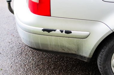Hasarlı araba tamponu ve gümüş renkli bir araçta çizikler var.