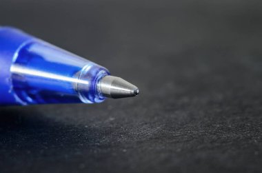 Koyu dokulu bir yüzey üzerinde mavi tükenmez kalem ucu aşırı yakın plan