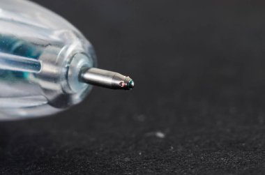 Tükenmez kalemin ucu, mavi mürekkep ve küçük kırmızı noktalı aşırı yakın çekim makro görüntüsü.
