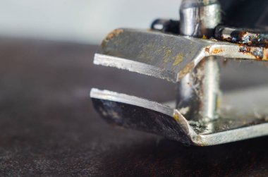 Karanlık bir yüzeyde paslı bir zımba çıkarıcının aşırı yakın çekimi