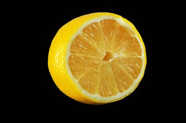 Işıl ışıl sarı bir limonun geniş açılı makro çekimi. Yarısı koyu siyah arkaplana karşı.