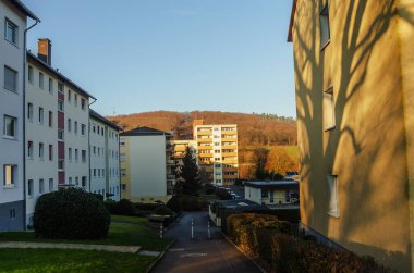 Apartman binaları sıcak altın saat güneşiyle yıkandı. Ön cephesinde ağaç gölgeleri vardı.